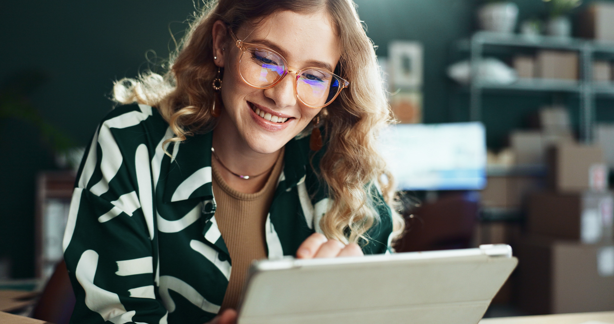 Woman outside smiling while looking at her laptop
