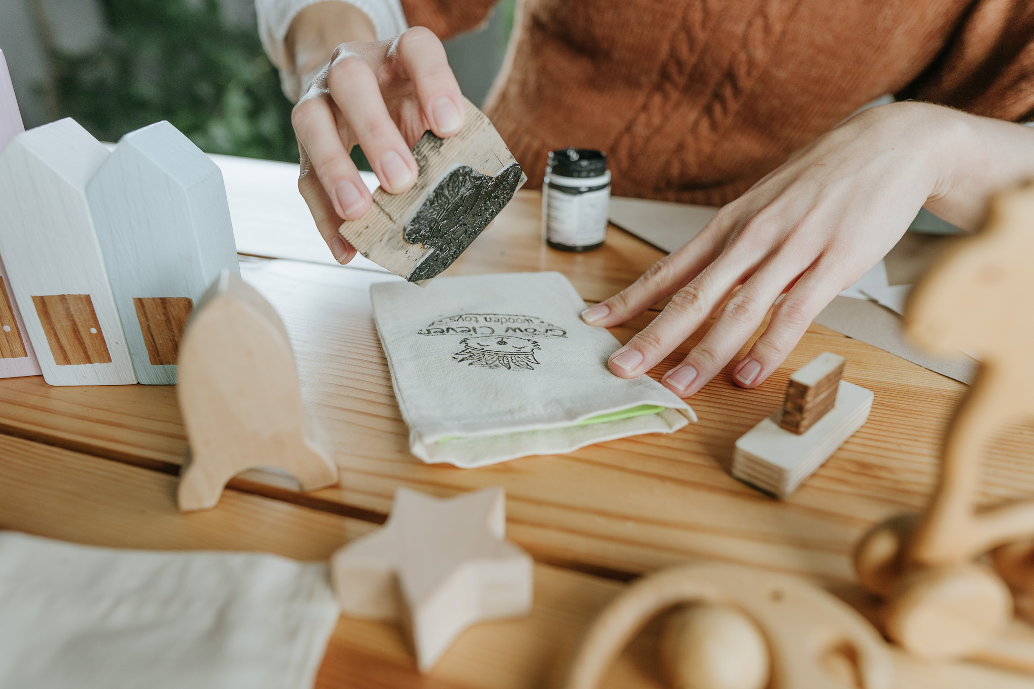 Artisan stamping cotton sachets with black branded stamp.