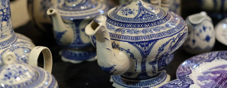 Close-up of blue and white vintage ceramic teapots and tableware, example of items to sell when learning how to sell vintage on Etsy